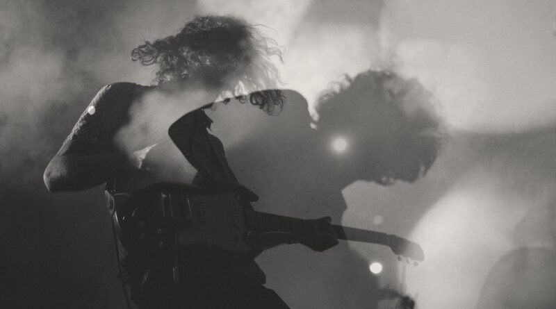 A black-and-white shot of a man playing electric guitar in double exposure