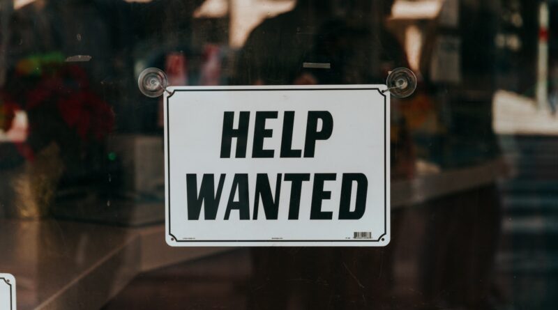 a sign that says help wanted on a glass door